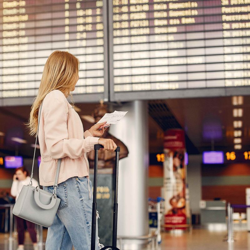 A shot of a traveler looking at a flight display board inside a sleek