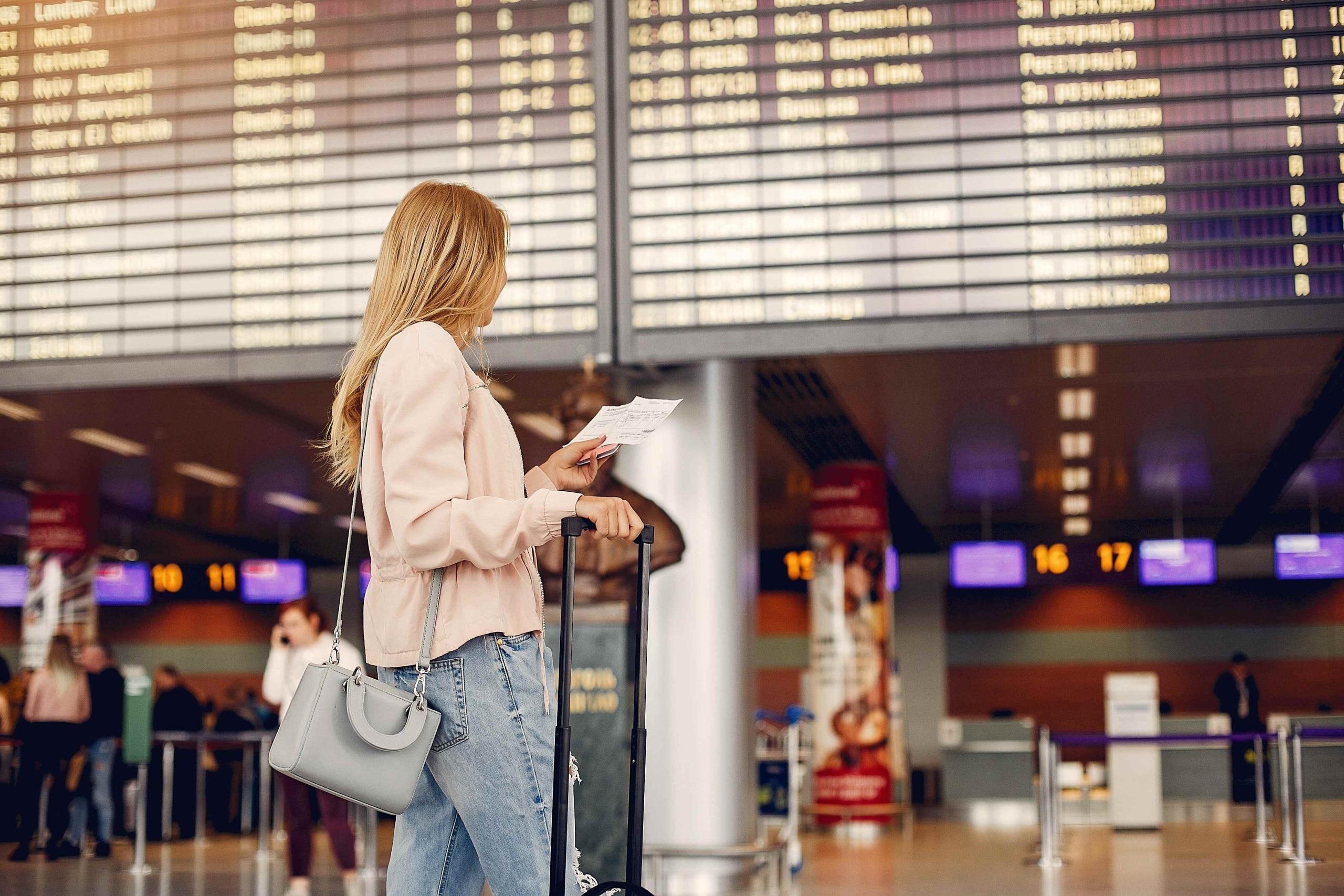 A shot of a traveler looking at a flight display board inside a sleek